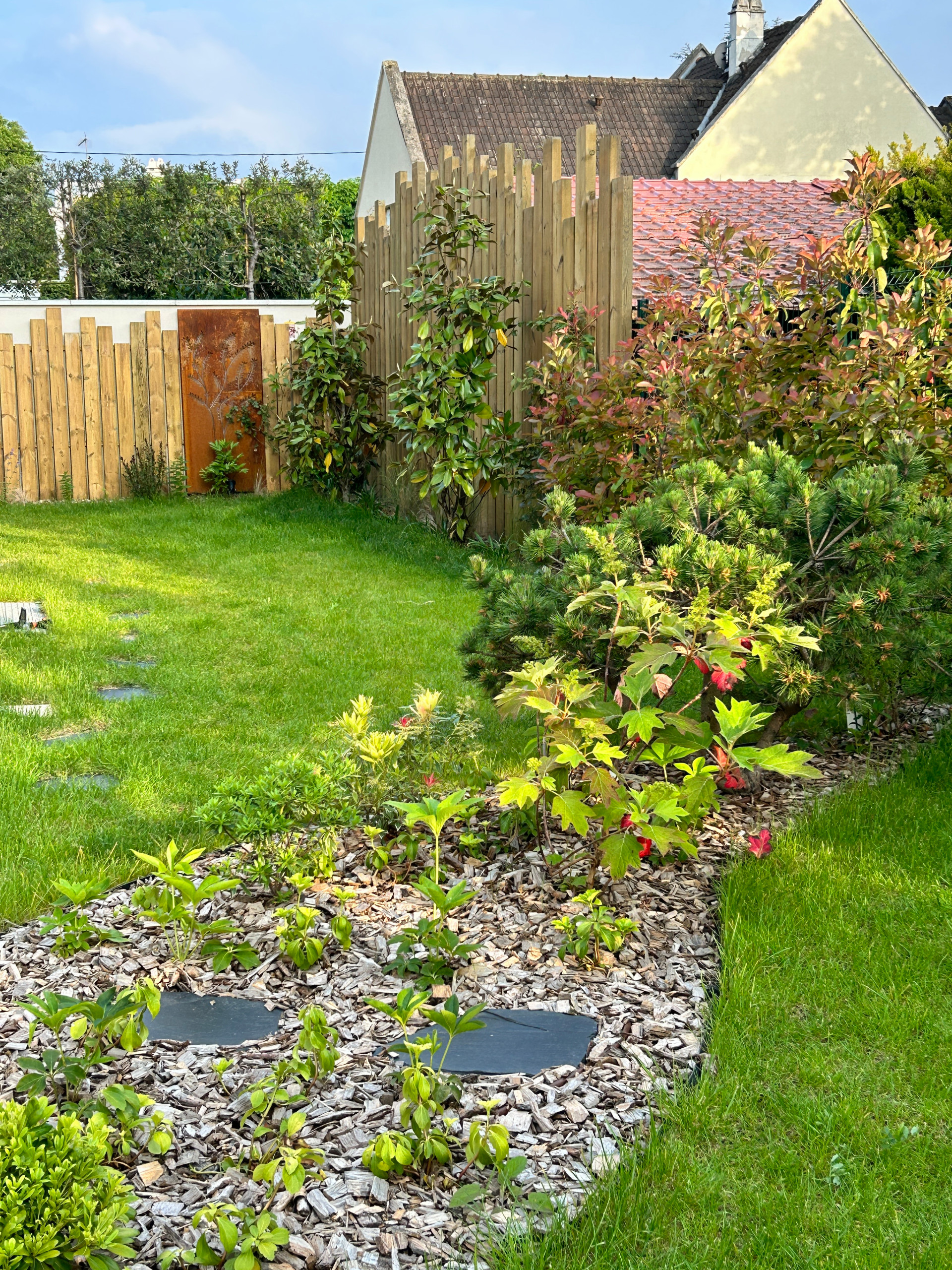 Aménagement du jardin avec des palissades en bois et des arbres palissés.