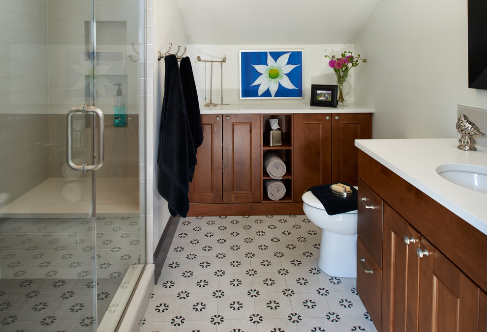 Design ideas for a mid-sized arts and crafts master bathroom in Denver with beaded inset cabinets, medium wood cabinets, a one-piece toilet, gray tile, porcelain tile, white walls, cement tiles, an undermount sink, engineered quartz benchtops, grey floor and a hinged shower door.