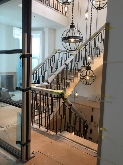 Expansive modern limestone spiral staircase in London with limestone risers and metal railing.