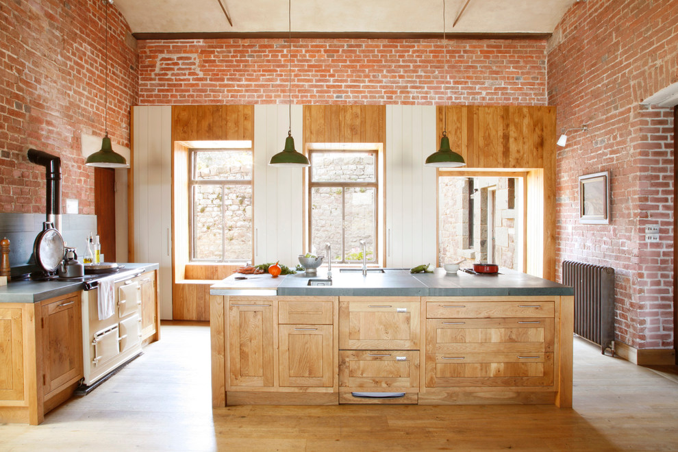 Photo of a country kitchen in London with an undermount sink, shaker cabinets, light wood cabinets, concrete benchtops, light hardwood floors and with island.