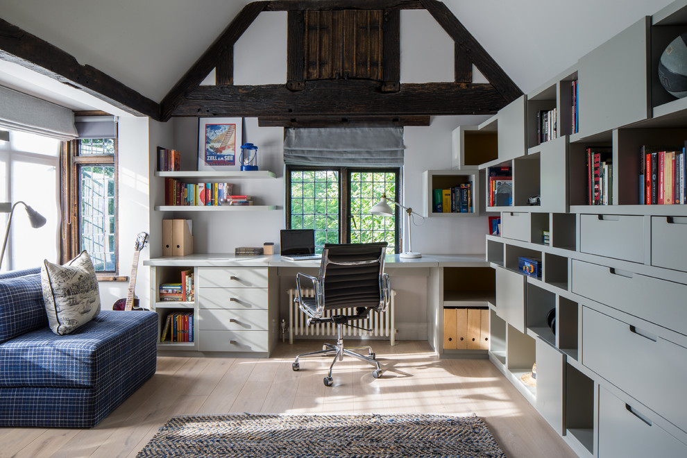 Country study room in London with white walls, light hardwood floors and a built-in desk.