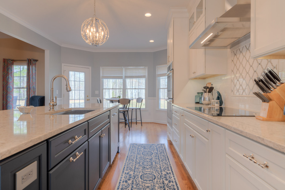 Eat-in kitchen - mid-sized transitional galley medium tone wood floor eat-in kitchen idea with an undermount sink, flat-panel cabinets, white cabinets, quartz countertops, white backsplash, subway tile backsplash, stainless steel appliances, an island and white countertops