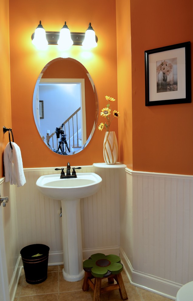 Photo of a small transitional 3/4 bathroom in New York with a one-piece toilet, orange walls, porcelain floors and a pedestal sink.