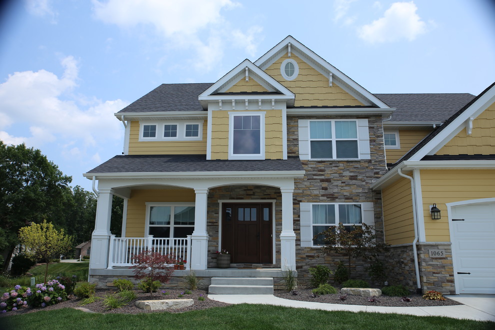 Photo of a mid-sized arts and crafts two-storey yellow exterior in Chicago with wood siding and a gable roof.