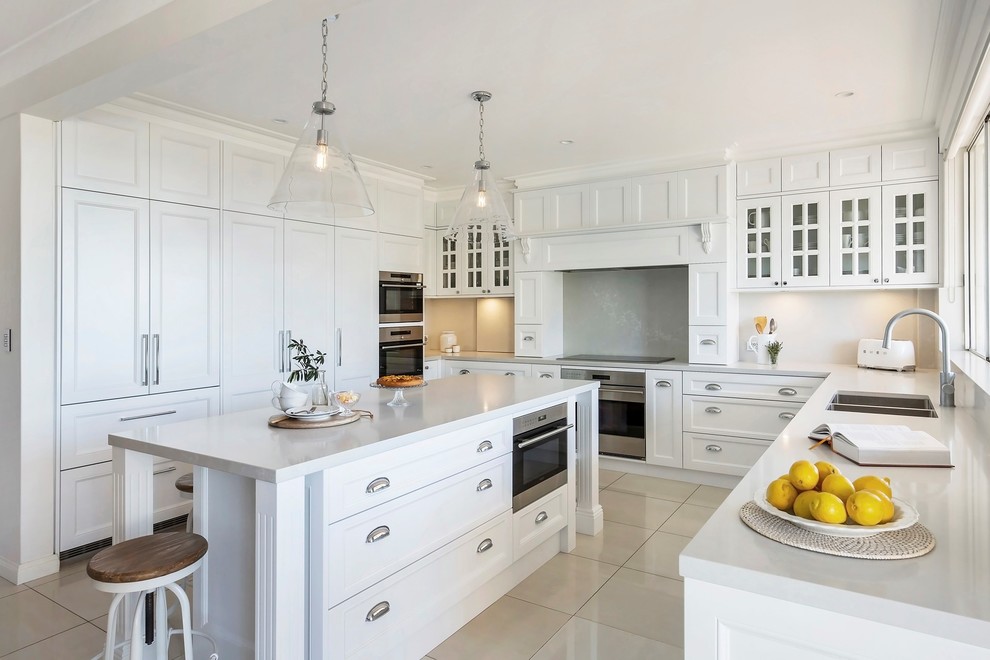 Inspiration for a large traditional u-shaped eat-in kitchen in Sydney with a double-bowl sink, recessed-panel cabinets, white cabinets, marble benchtops, white splashback, stainless steel appliances, porcelain floors, with island, white floor and white benchtop.