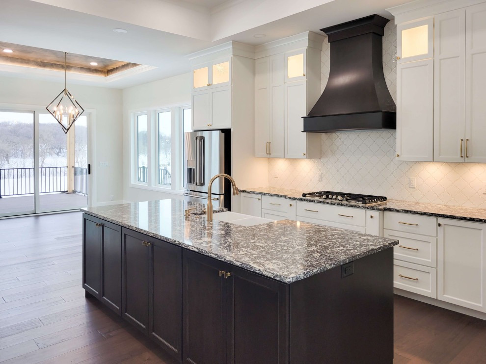 Example of a large transitional l-shaped medium tone wood floor, brown floor and coffered ceiling eat-in kitchen design with a farmhouse sink, recessed-panel cabinets, white cabinets, quartz countertops, white backsplash, quartz backsplash, stainless steel appliances, two islands and multicolored countertops