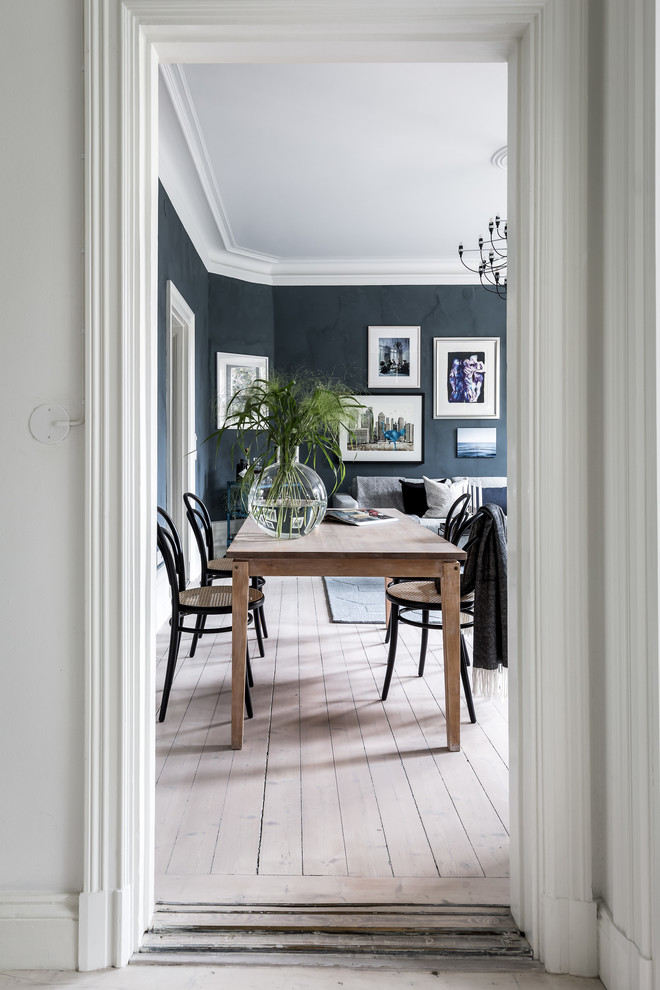 This is an example of a scandinavian dining room in Stockholm with black walls, light hardwood floors, no fireplace and beige floor.