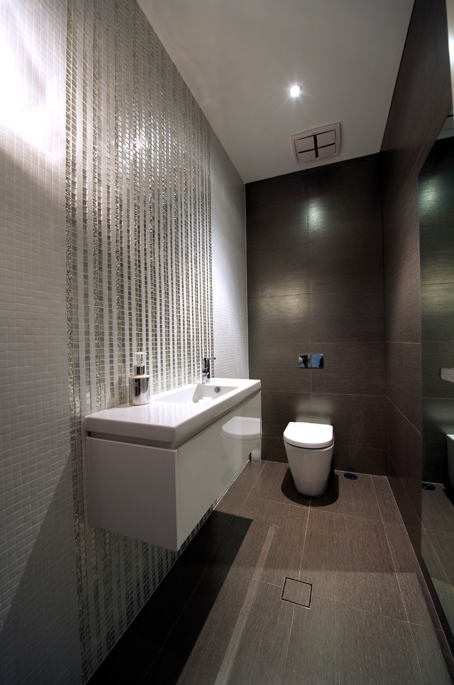 This is an example of a contemporary powder room in Sydney with a wall-mount sink, white cabinets, a one-piece toilet, mosaic tile and porcelain floors.
