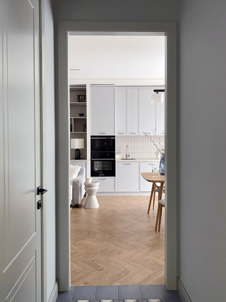 This is an example of a mid-sized transitional galley eat-in kitchen in Moscow with a drop-in sink, beaded inset cabinets, grey cabinets, laminate benchtops, beige splashback, subway tile splashback, black appliances, porcelain floors, no island, brown floor and beige benchtop.
