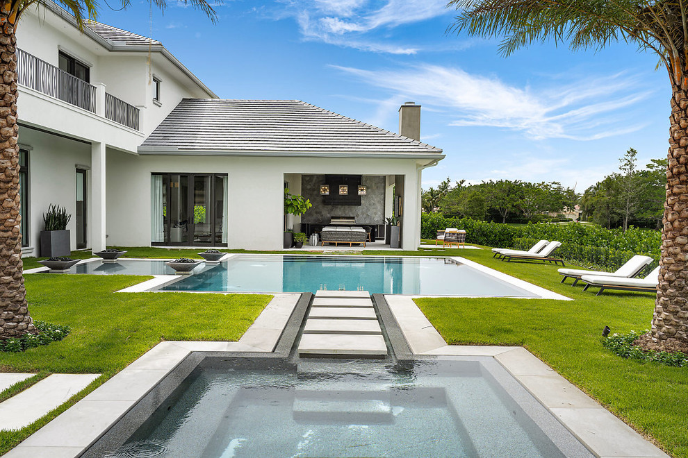 Beach style backyard custom-shaped pool in Miami with a hot tub.