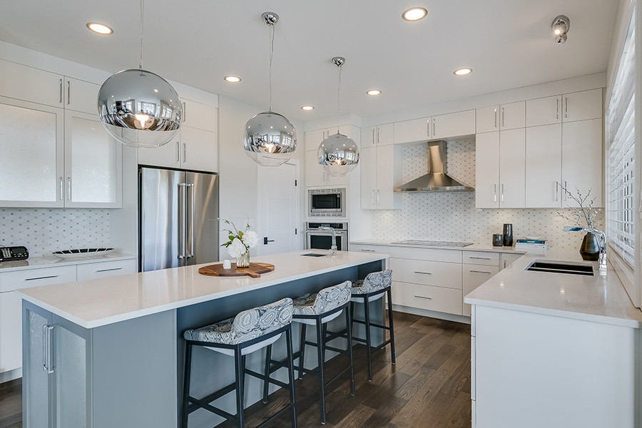 This is an example of a mid-sized contemporary u-shaped separate kitchen in Other with a double-bowl sink, flat-panel cabinets, white cabinets, quartzite benchtops, white splashback, ceramic splashback, stainless steel appliances, dark hardwood floors, with island and brown floor.