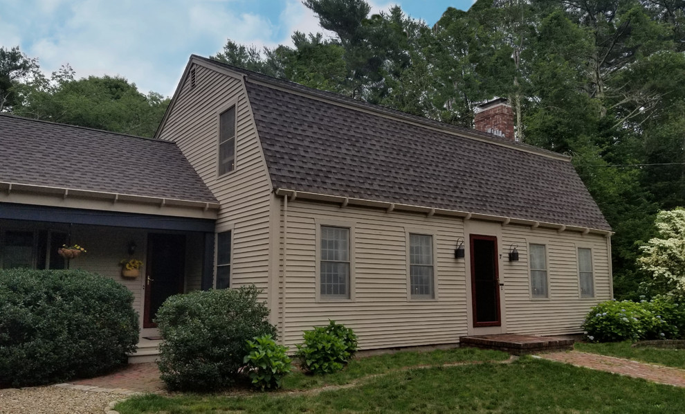 This is an example of a mid-sized traditional beige house exterior in Boston with a gambrel roof and a shingle roof.