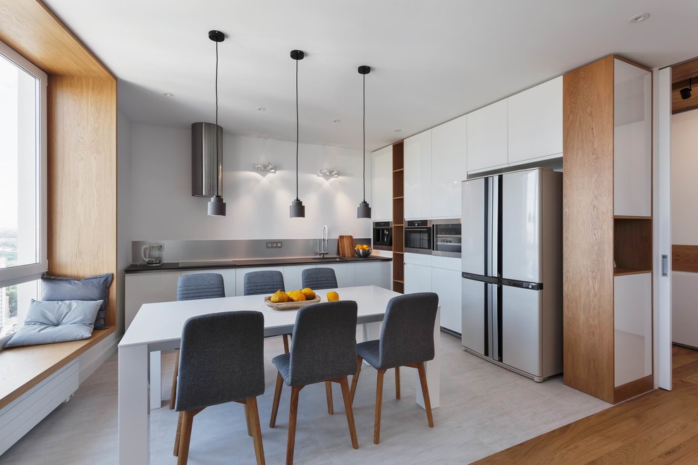 This is an example of a large contemporary l-shaped open plan kitchen in Yekaterinburg with flat-panel cabinets, white cabinets, metallic splashback, stainless steel appliances, ceramic floors, no island, grey floor, an undermount sink and metal splashback.
