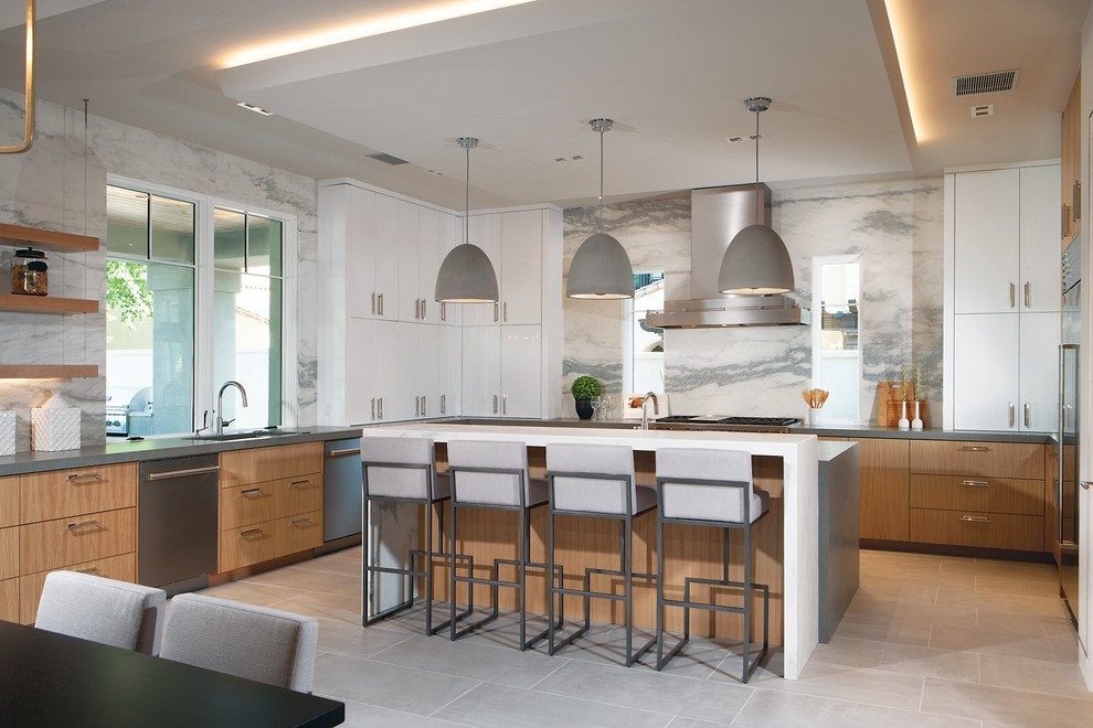 Design ideas for a large contemporary u-shaped eat-in kitchen in Phoenix with an undermount sink, flat-panel cabinets, medium wood cabinets, white splashback, stainless steel appliances, with island, grey benchtop, quartz benchtops, stone slab splashback, porcelain floors and grey floor.