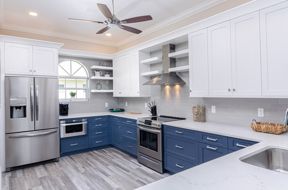Design ideas for a transitional u-shaped kitchen in Miami with an undermount sink, shaker cabinets, white cabinets, grey splashback, subway tile splashback, stainless steel appliances, medium hardwood floors, a peninsula, brown floor and white benchtop.