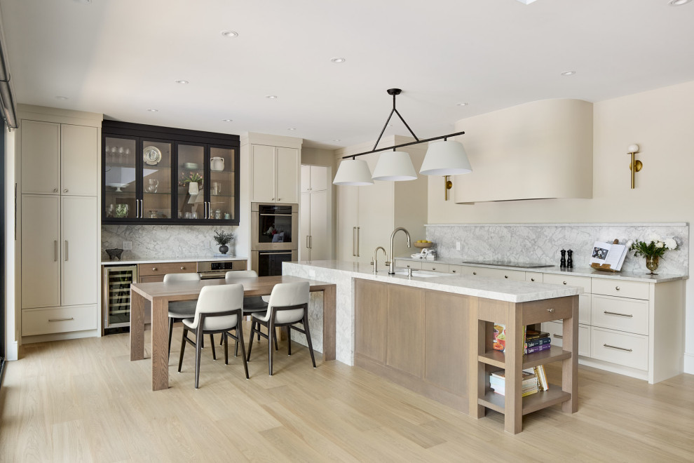 Example of a large transitional l-shaped light wood floor and beige floor eat-in kitchen design with shaker cabinets, beige cabinets, quartz countertops, multicolored backsplash, quartz backsplash, stainless steel appliances, an island, white countertops and an undermount sink