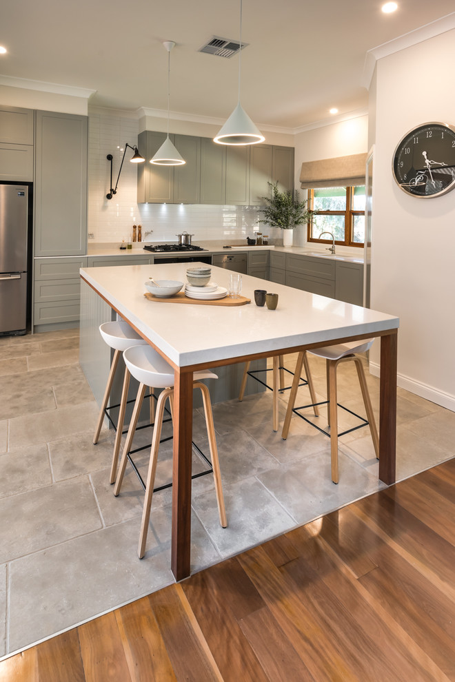 Photo of a large contemporary l-shaped open plan kitchen in Adelaide with grey cabinets, white splashback, subway tile splashback, stainless steel appliances, terra-cotta floors, with island, white benchtop, an undermount sink, grey floor, shaker cabinets and quartz benchtops.