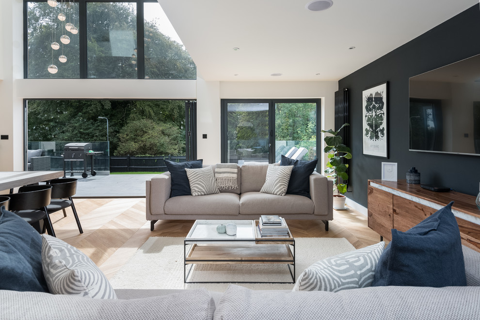 Contemporary open concept living room in Sussex with white walls, a wall-mounted tv and beige floor.
