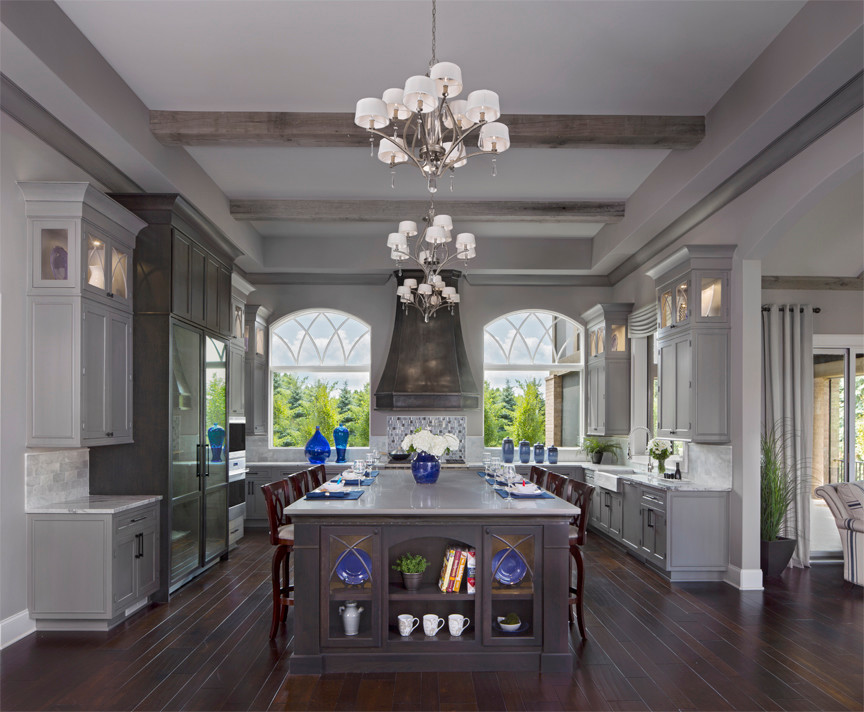 Example of a huge transitional u-shaped dark wood floor open concept kitchen design with a farmhouse sink, recessed-panel cabinets, gray cabinets, granite countertops, gray backsplash, stainless steel appliances and an island