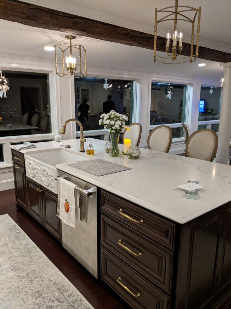 Design ideas for a large galley kitchen/diner in New York with a belfast sink, raised-panel cabinets, dark wood cabinets, engineered stone countertops, stainless steel appliances, dark hardwood flooring, an island, brown floors and white worktops.