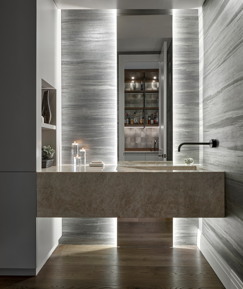 Contemporary cloakroom in Chicago with an integrated sink, marble worktops, feature lighting, a floating vanity unit, wallpapered walls, grey walls, medium hardwood flooring, brown floors and grey worktops.