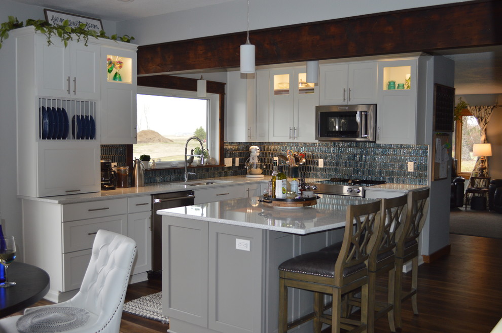 Eat-in kitchen - mid-sized transitional l-shaped brown floor eat-in kitchen idea with a double-bowl sink, shaker cabinets, white cabinets, quartzite countertops, multicolored backsplash, glass tile backsplash, stainless steel appliances, an island and white countertops