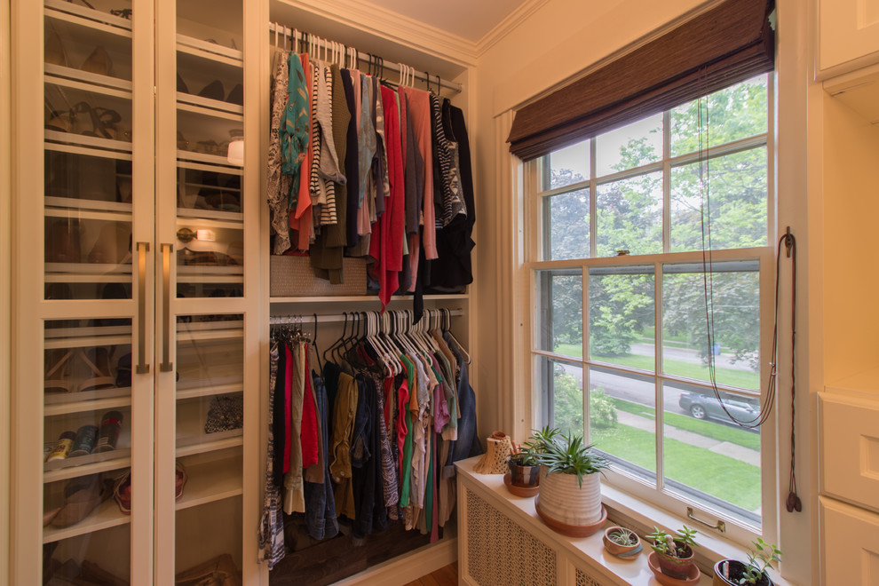This is an example of a traditional walk-in wardrobe in Minneapolis with glass-front cabinets, white cabinets, medium hardwood floors and brown floor.