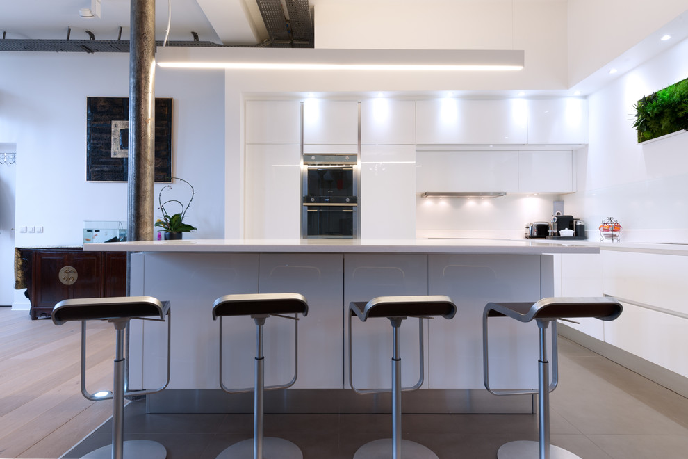 Inspiration for a mid-sized modern l-shaped open plan kitchen in Paris with an integrated sink, beaded inset cabinets, white cabinets, quartzite benchtops, white splashback, glass tile splashback, panelled appliances, terra-cotta floors and with island.