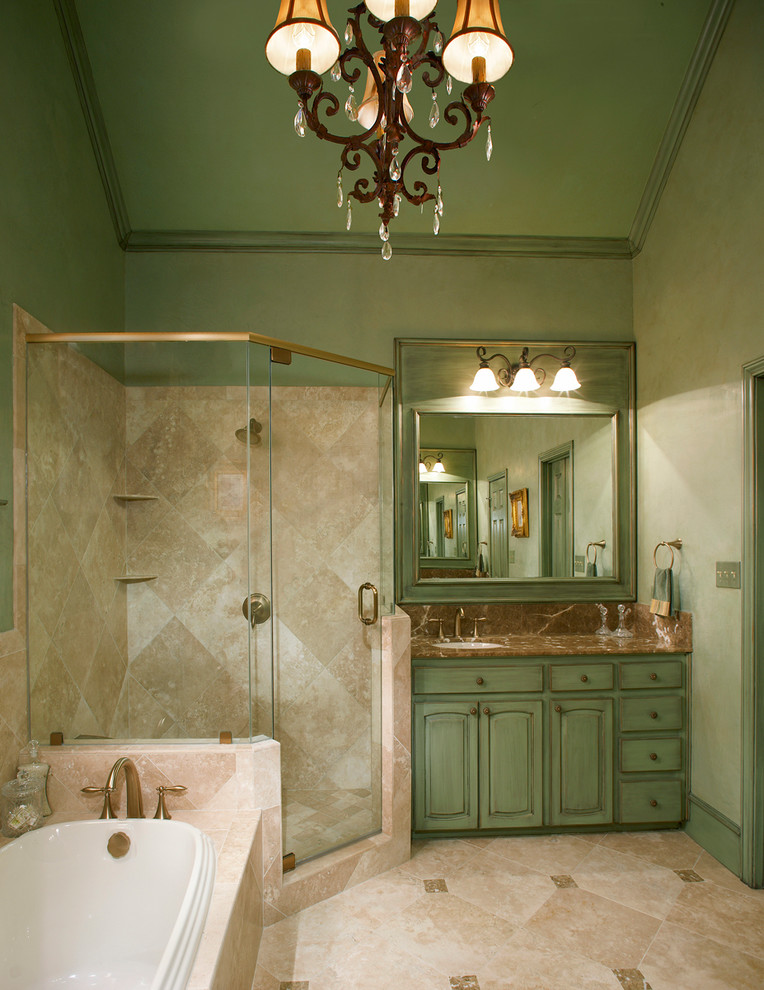 Design ideas for a small mediterranean master bathroom in Dallas with raised-panel cabinets, a drop-in tub, a corner shower, brown tile, stone tile, travertine floors, an undermount sink, marble benchtops, green cabinets, green walls, brown floor and a hinged shower door.