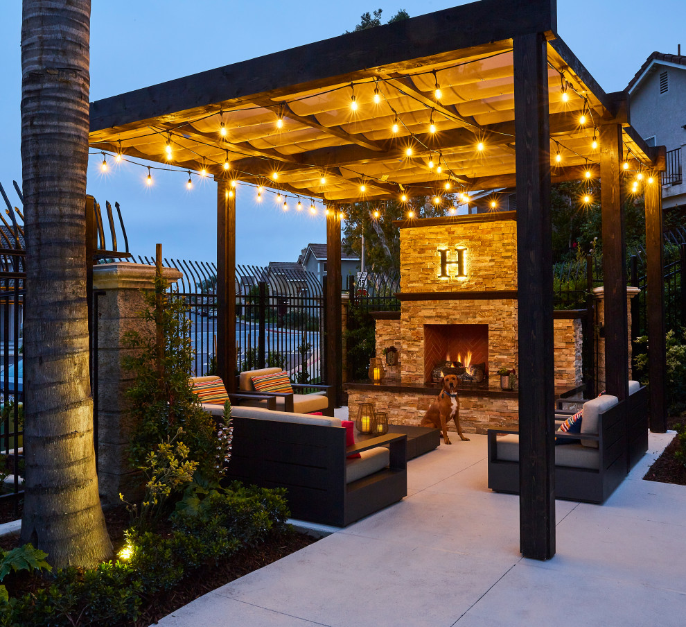 Inspiration for a large mediterranean courtyard patio in Orange County with with fireplace, decking and a pergola.