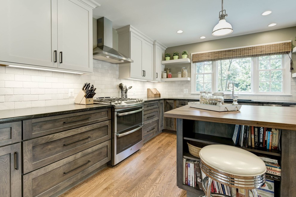 Mid-sized transitional l-shaped separate kitchen in DC Metro with an undermount sink, shaker cabinets, dark wood cabinets, soapstone benchtops, beige splashback, stone tile splashback, stainless steel appliances, light hardwood floors, with island and brown floor.