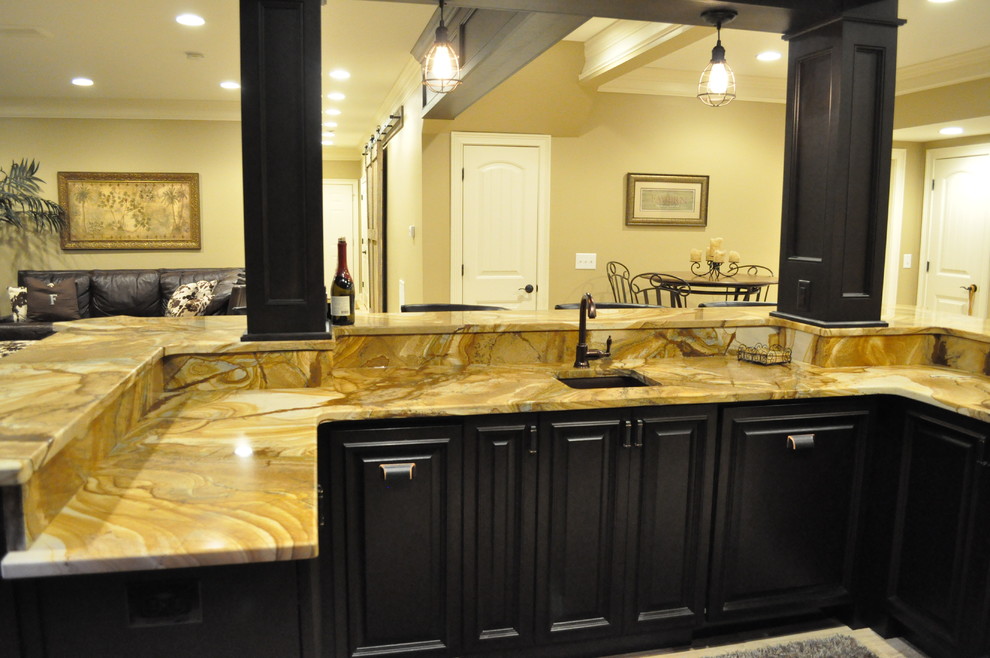 Inspiration for a large traditional u-shaped seated home bar in Atlanta with an undermount sink, raised-panel cabinets, dark wood cabinets, onyx benchtops, beige splashback and light hardwood floors.
