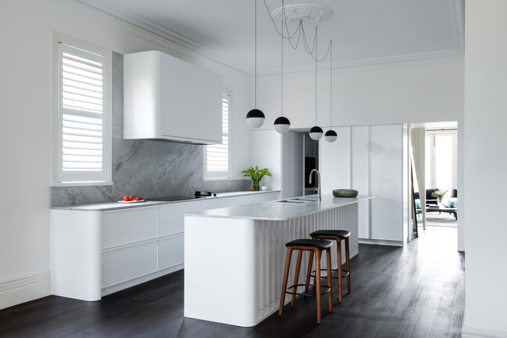 Photo of a large contemporary l-shaped kitchen pantry in Sydney with an undermount sink, shaker cabinets, white cabinets, marble benchtops, white splashback, stone slab splashback, black appliances, dark hardwood floors, with island and white benchtop.