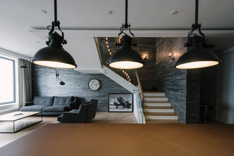 This is an example of a large industrial open concept living room in Moscow with a home bar, beige walls, light hardwood floors, a wall-mounted tv and beige floor.