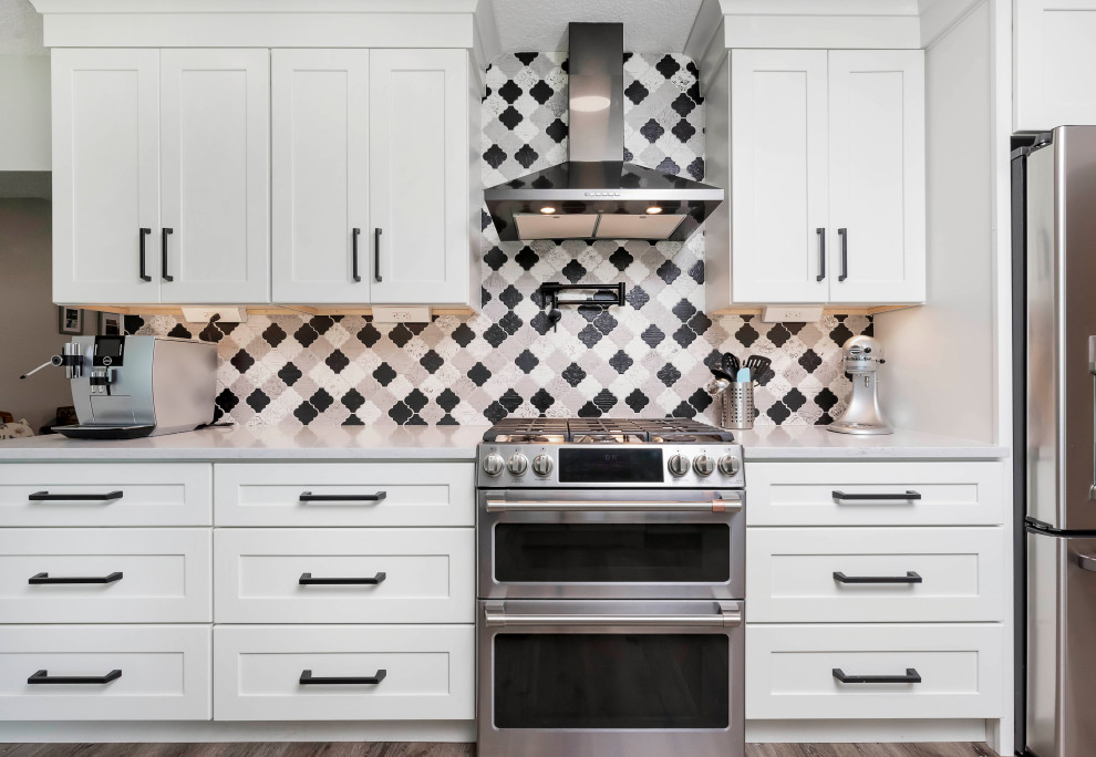 Kitchen pantry - large transitional vinyl floor and brown floor kitchen pantry idea in Orlando with an undermount sink, shaker cabinets, white cabinets, quartzite countertops, multicolored backsplash, porcelain backsplash, stainless steel appliances, an island and white countertops