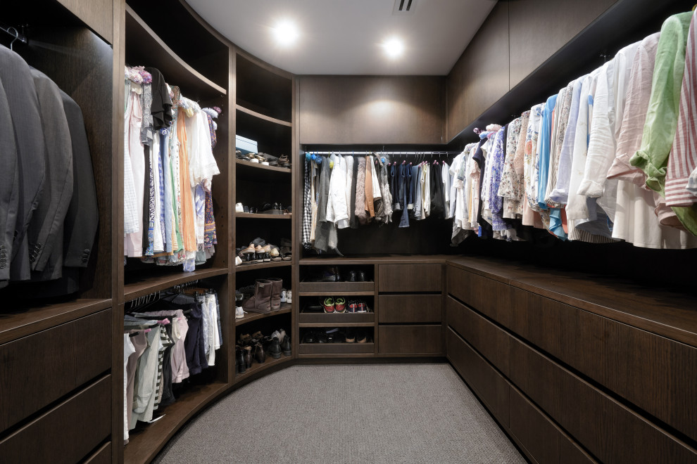 Photo of a large contemporary gender-neutral dressing room in Perth with flat-panel cabinets, dark wood cabinets, carpet and grey floor.