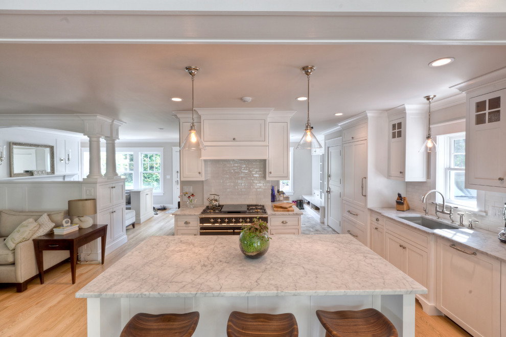 Inspiration for a traditional single-wall open plan kitchen in New York with a single-bowl sink, shaker cabinets, white cabinets, marble benchtops, white splashback, subway tile splashback, light hardwood floors and with island.