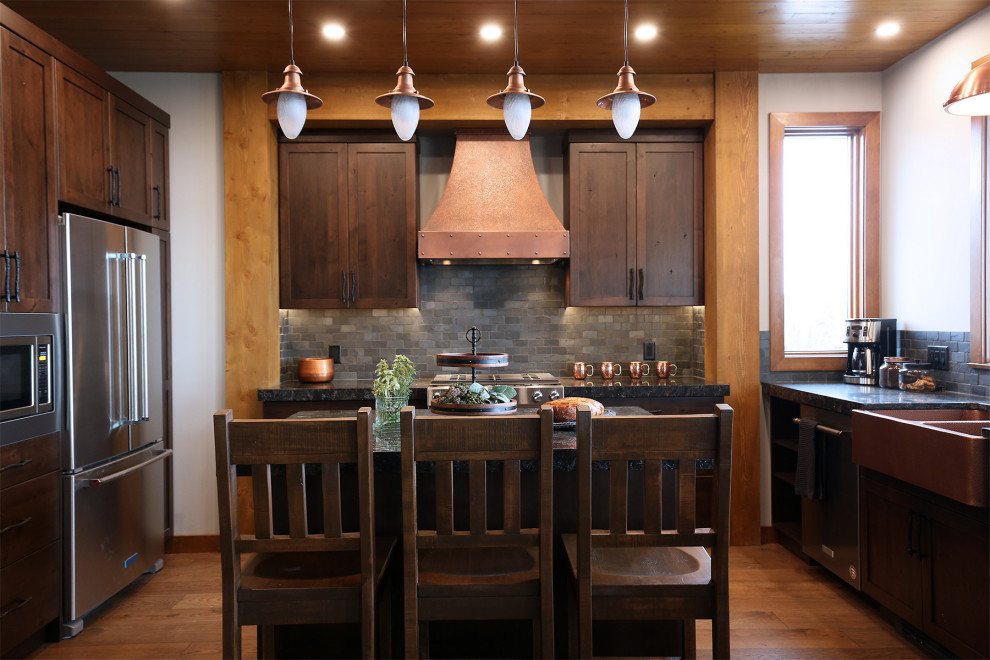 Idéer för att renovera ett rustikt svart svart kök med öppen planlösning, med en rustik diskho, skåp i shakerstil, skåp i mellenmörkt trä, bänkskiva i kvartsit, svart stänkskydd, stänkskydd i skiffer, rostfria vitvaror, mellanmörkt trägolv, en köksö och brunt golv