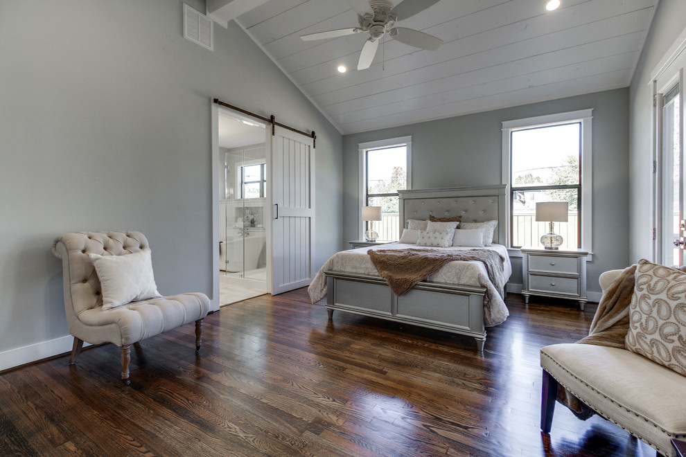 Large country master bedroom in Houston with blue walls, medium hardwood floors and brown floor.