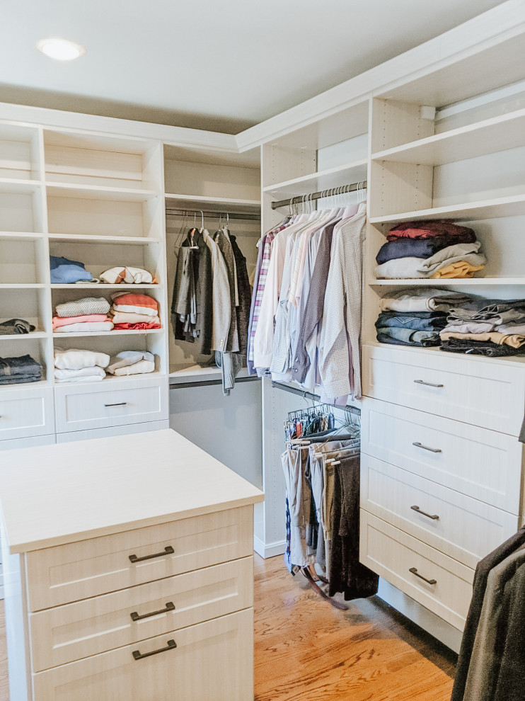 Mid-sized traditional gender-neutral walk-in wardrobe in New York with recessed-panel cabinets, light wood cabinets, medium hardwood floors and brown floor.