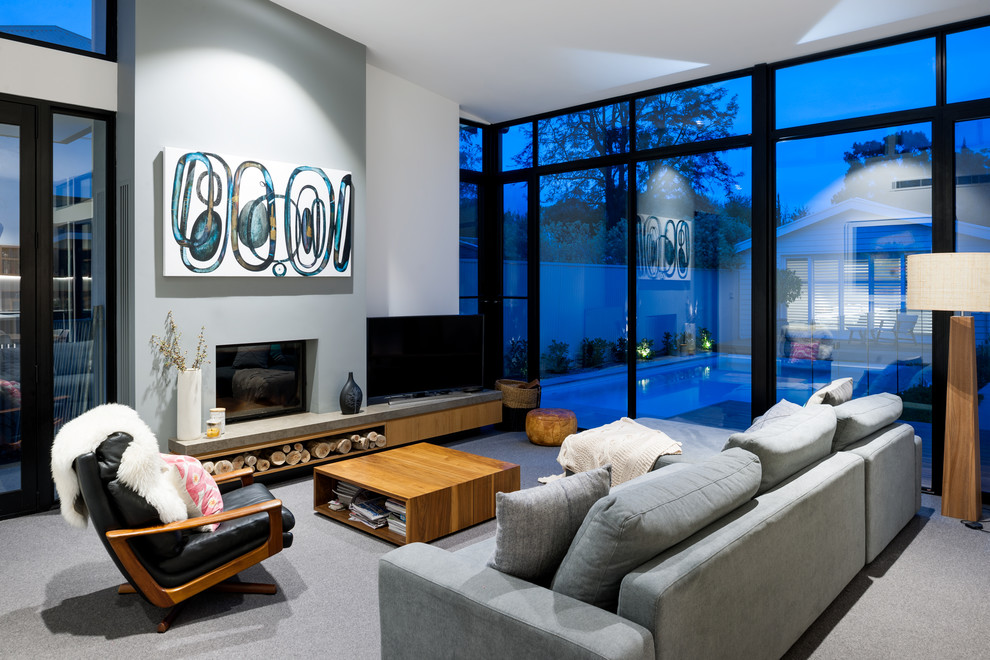 This is an example of a contemporary living room in Adelaide with white walls, carpet, a standard fireplace and grey floor.