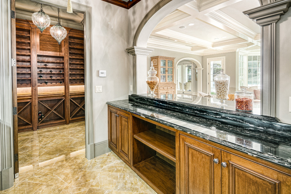 This is an example of a transitional galley wet bar in Los Angeles with recessed-panel cabinets, medium wood cabinets, marble benchtops, porcelain floors, beige floor and green benchtop.