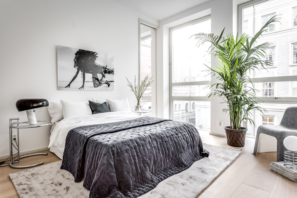 Mid-sized contemporary master bedroom in Stockholm with white walls, light hardwood floors and beige floor.
