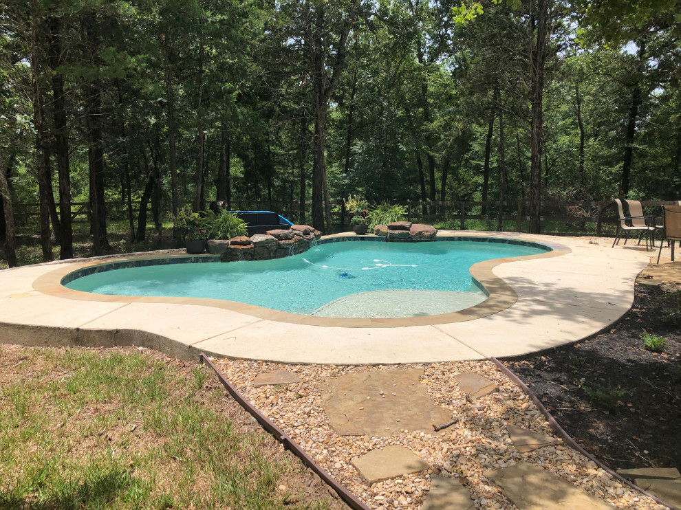 Design ideas for a mid-sized country backyard custom-shaped natural pool in Other with with privacy feature and concrete slab.