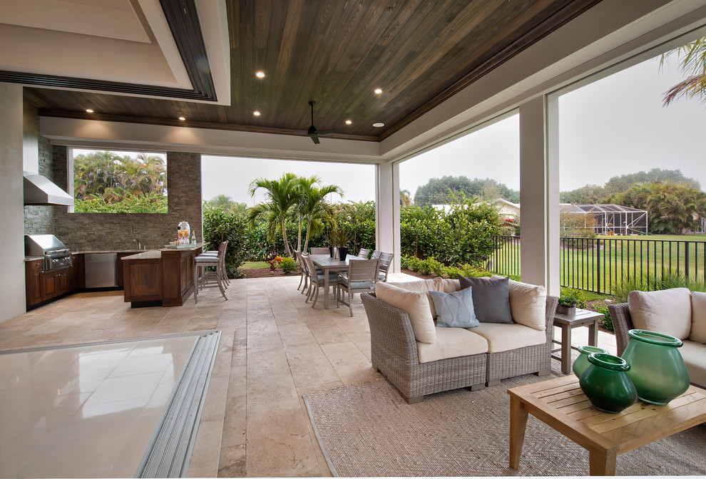 Photo of an expansive transitional backyard patio in Tampa with an outdoor kitchen, natural stone pavers and a roof extension.