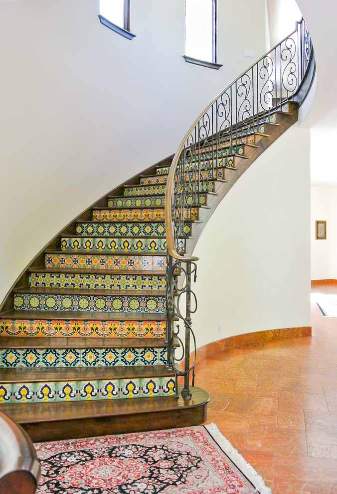 This is an example of an expansive mediterranean wood curved staircase in San Francisco with tile risers.