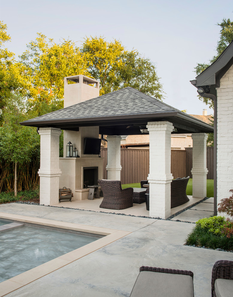 This is an example of a small transitional backyard patio in Dallas with a fire feature, natural stone pavers and a roof extension.