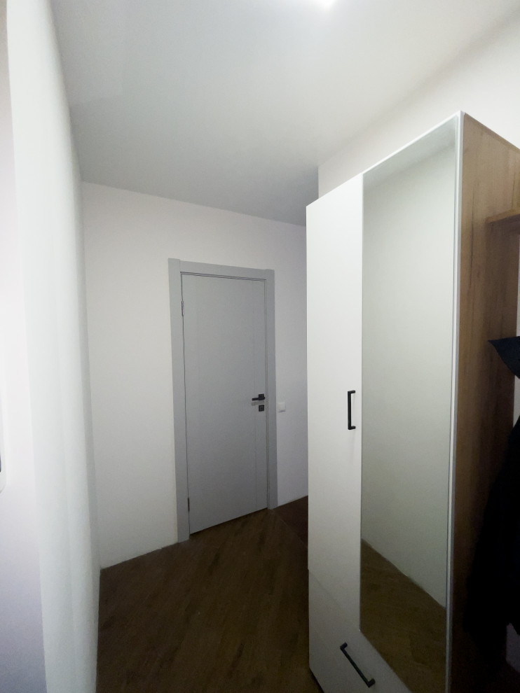На фото: узкий коридор среднего размера в современном стиле с белыми стенами, паркетным полом среднего тона, коричневым полом и обоями на стенах