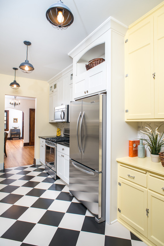 Traditional kitchen in Detroit with shaker cabinets, yellow cabinets, white splashback, stainless steel appliances, multi-coloured floor and yellow benchtop.