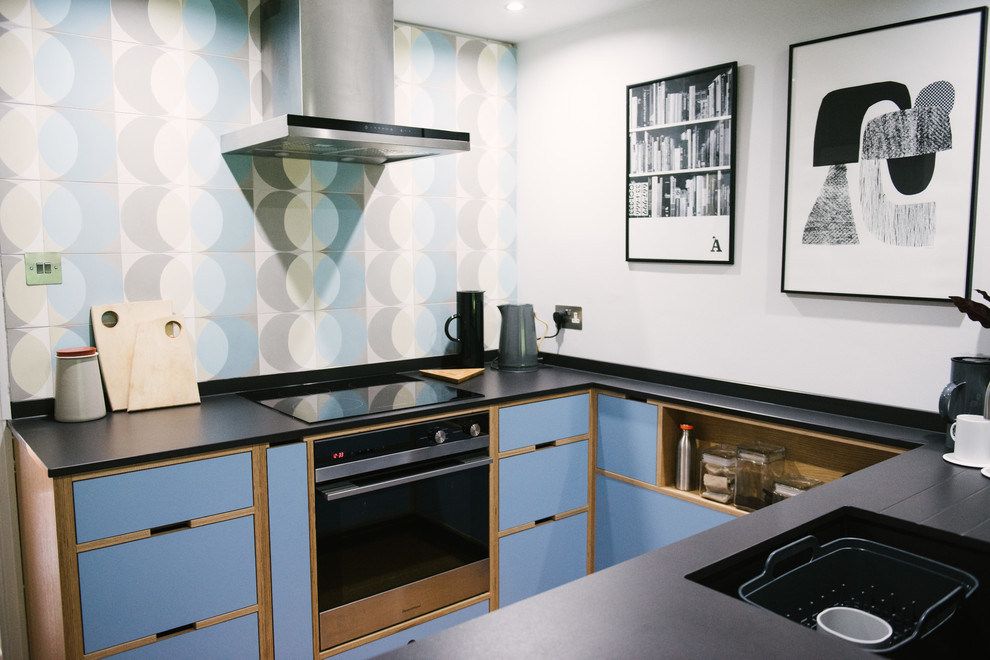 Photo of a small midcentury u-shaped kitchen in Other with flat-panel cabinets, blue cabinets, no island, black benchtop, an integrated sink, blue splashback and black appliances.